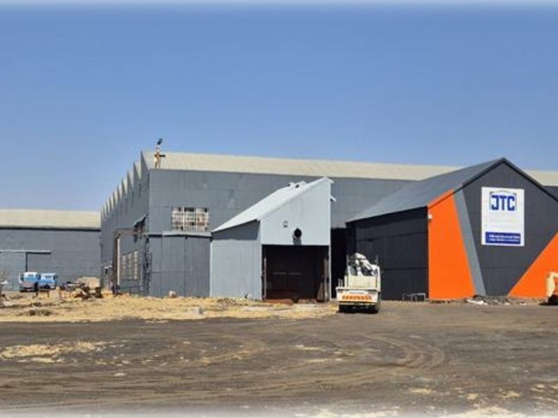 Exterior view of a large industrial warehouse facility featuring metal cladding, roller shutter access, and an expansive yard area.