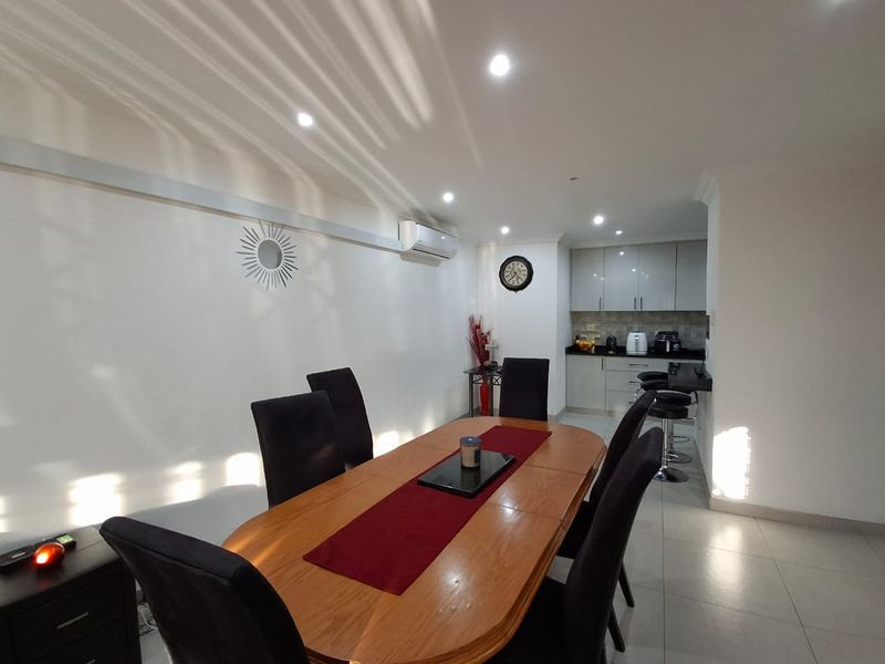Open-plan dining and kitchen area featuring tiled flooring, recessed lighting, a split-system air conditioner, and modern built-in cabinetry.