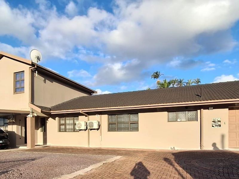 Front elevation of a multi-level residential property featuring a paved driveway, integrated garage, and neutral exterior finish.