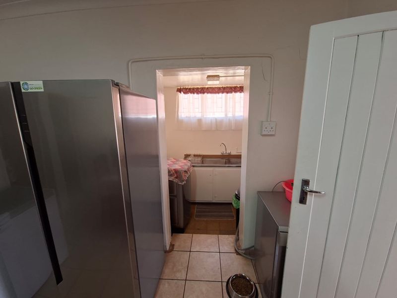 A functional scullery area featuring a double sink, built-in cabinetry, and tiled flooring, providing a practical space for kitchen preparation and wash-up tasks.