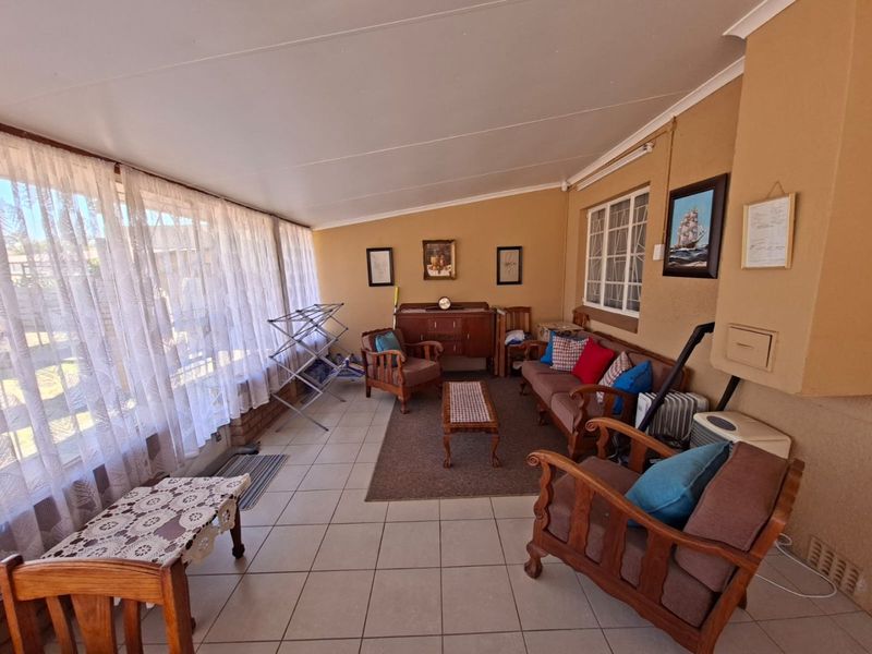 A spacious enclosed patio area featuring tiled flooring and large windows, providing a bright and versatile living space.