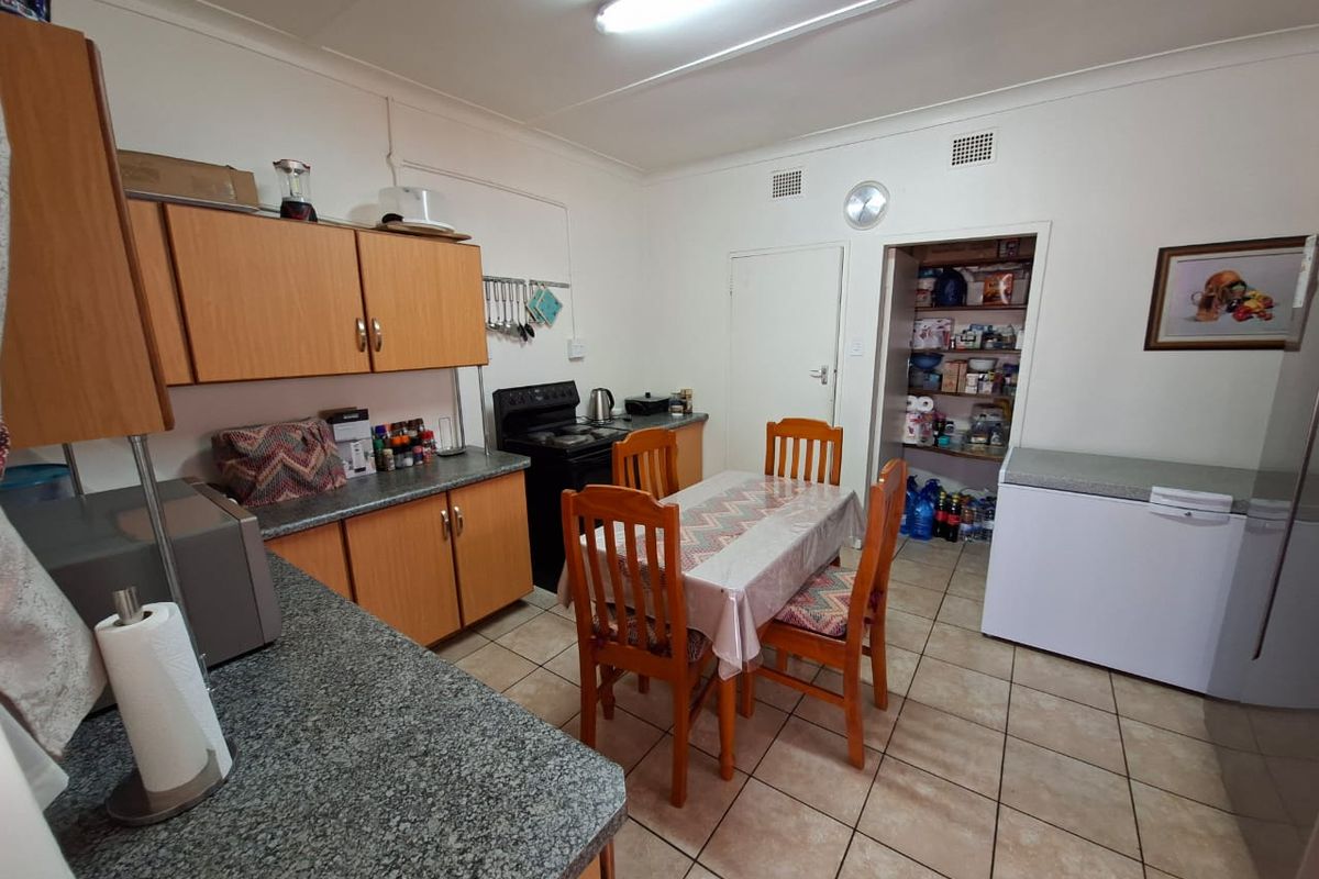 A functional kitchen featuring laminate cabinetry, granite countertops, tiled flooring, and a convenient walk-in pantry for additional storage.