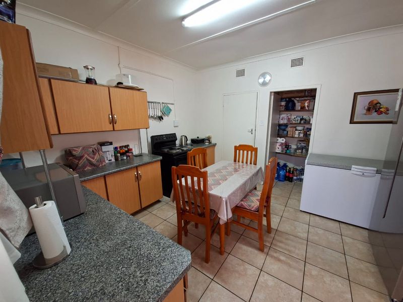 A functional kitchen featuring laminate cabinetry, granite countertops, tiled flooring, and a convenient walk-in pantry for additional storage.