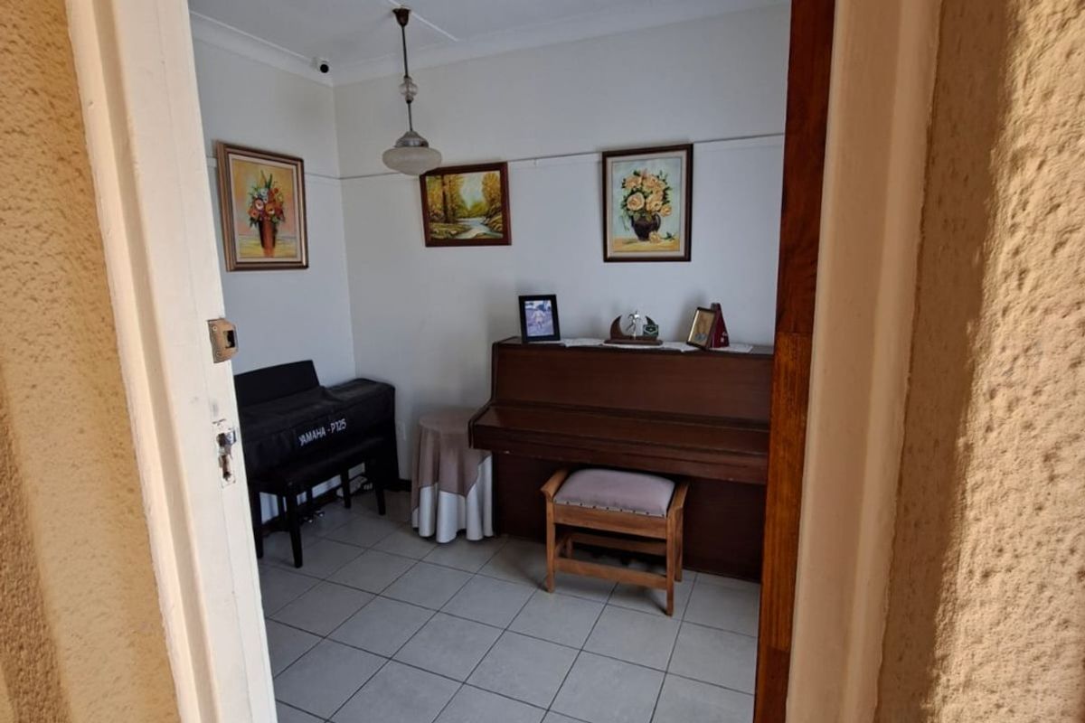 A view into a living area featuring tiled flooring and a central pendant light fixture, viewed through a doorway.
