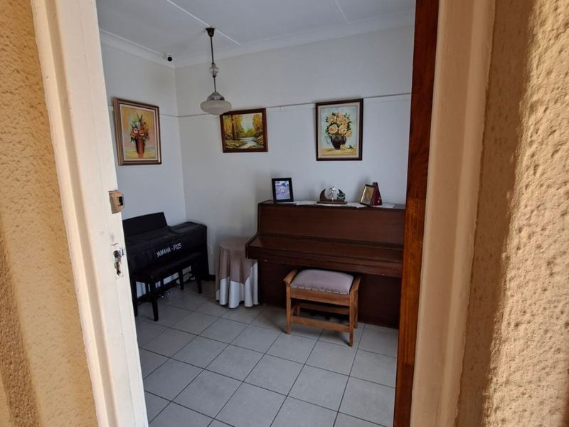 A view into a living area featuring tiled flooring and a central pendant light fixture, viewed through a doorway.