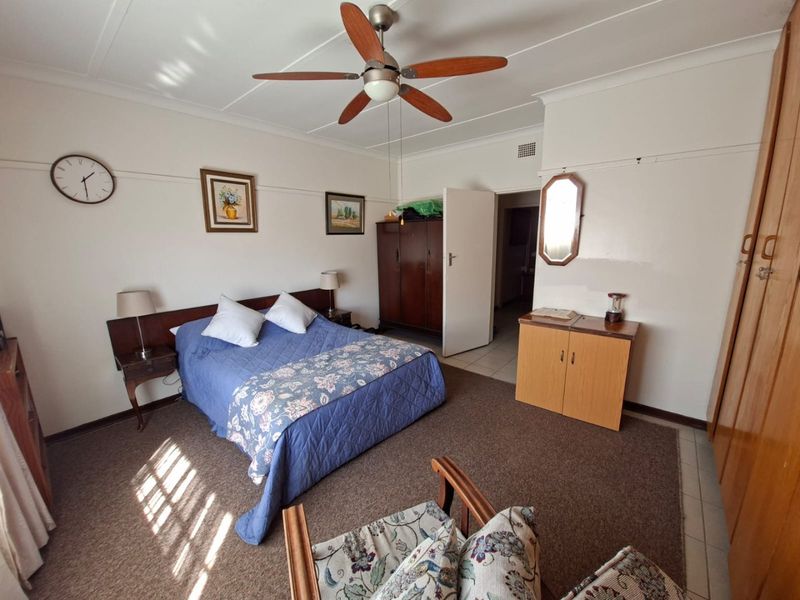 A spacious bedroom featuring a ceiling fan, built-in storage cupboards, and classic picture rail detailing, offering a functional and well-maintained living space.