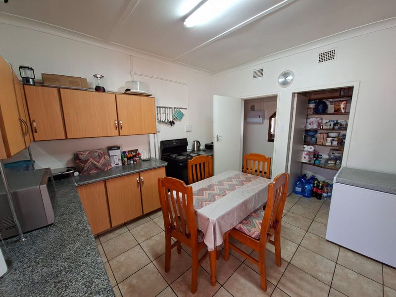 Functional kitchen featuring laminate cabinetry, granite-look countertops, a freestanding stove, and a convenient walk-in pantry with tiled flooring throughout.