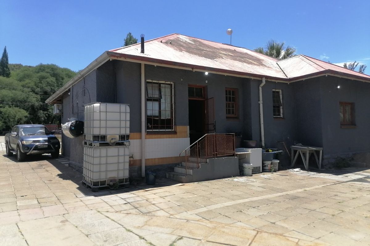 Rear view of the property featuring a metal roof, paved patio area, and external staircase access.
