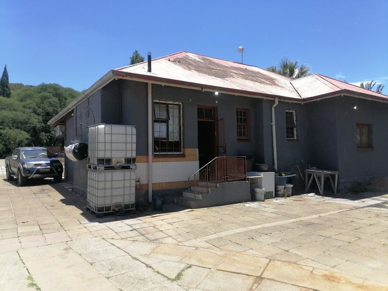 Rear view of the property featuring a metal roof, paved patio area, and external staircase access.