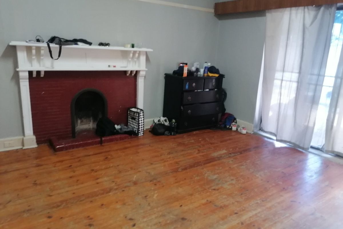 Living room featuring a traditional fireplace, original timber flooring, and sliding glass door access to the exterior.