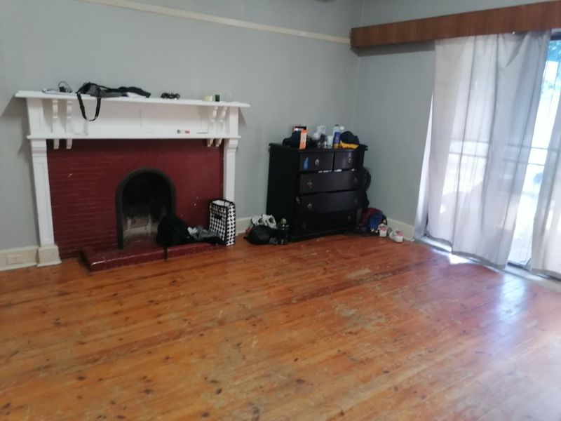 Living room featuring a traditional fireplace, original timber flooring, and sliding glass door access to the exterior.