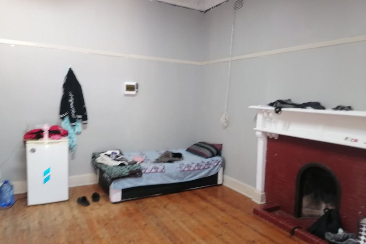 A bedroom featuring original timber flooring, a traditional fireplace with a mantelpiece, and classic picture rail detailing.