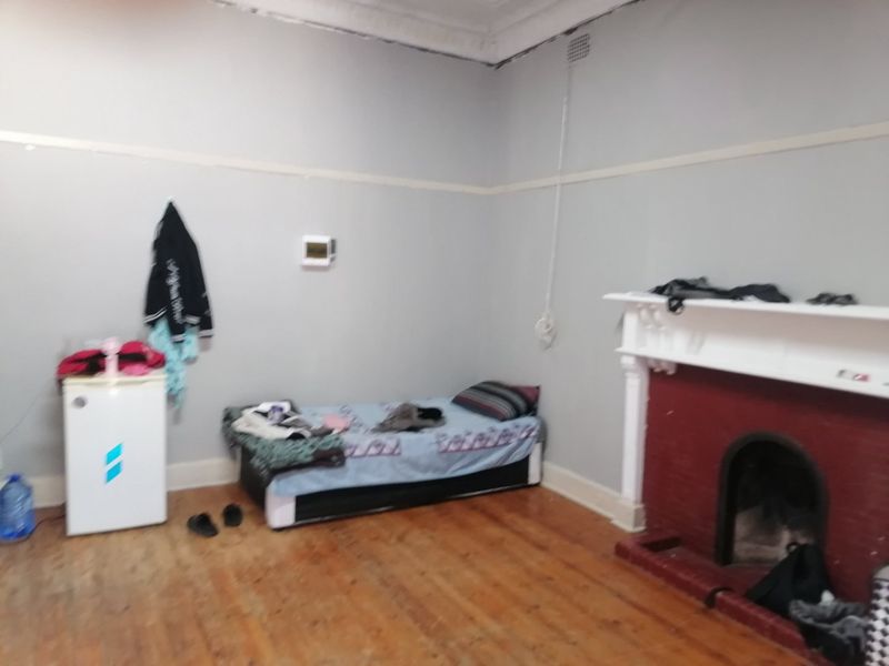 A bedroom featuring original timber flooring, a traditional fireplace with a mantelpiece, and classic picture rail detailing.