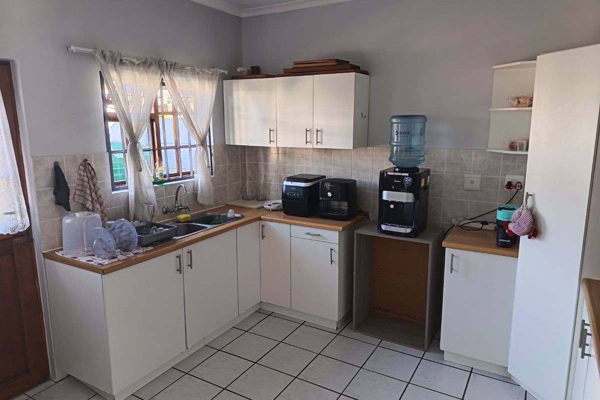 A functional kitchen featuring white cabinetry, laminate countertops, tiled backsplash, and ceramic floor tiles, providing a practical workspace with room for updates.