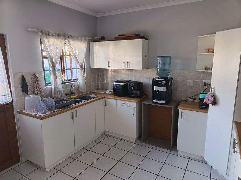A functional kitchen featuring white cabinetry, laminate countertops, tiled backsplash, and ceramic floor tiles, providing a practical workspace with room for updates.