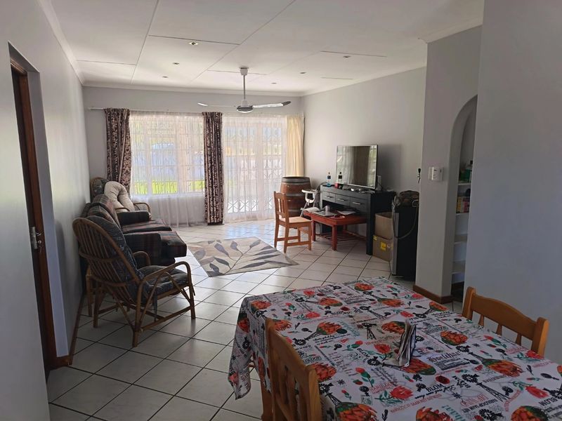 Spacious open-plan living and dining area featuring tiled flooring, recessed lighting, and large sliding glass doors providing natural light.