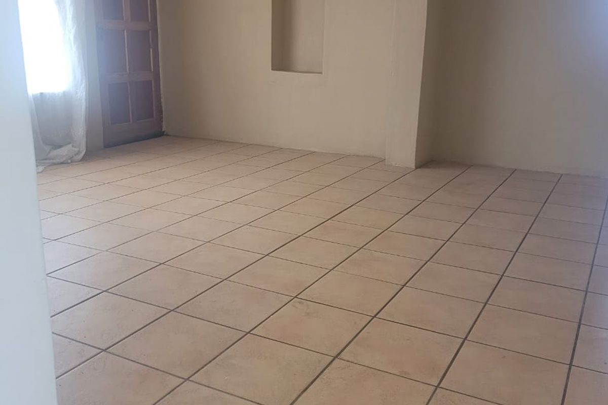 An empty living area featuring neutral tiled flooring, a built-in wall niche, and a timber entrance door.