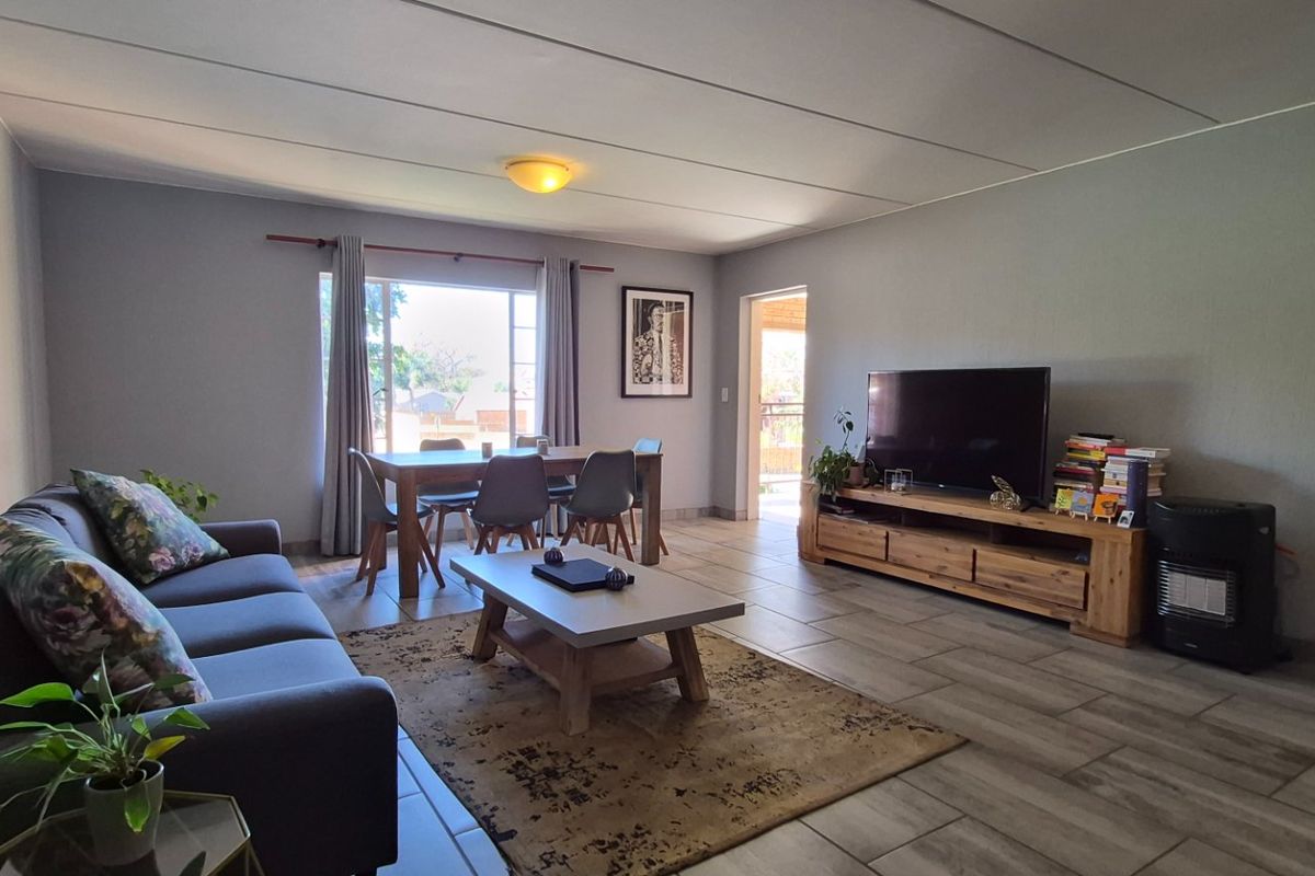 A spacious living room featuring tiled flooring and neutral wall finishes, providing a comfortable and functional area for relaxation and dining.