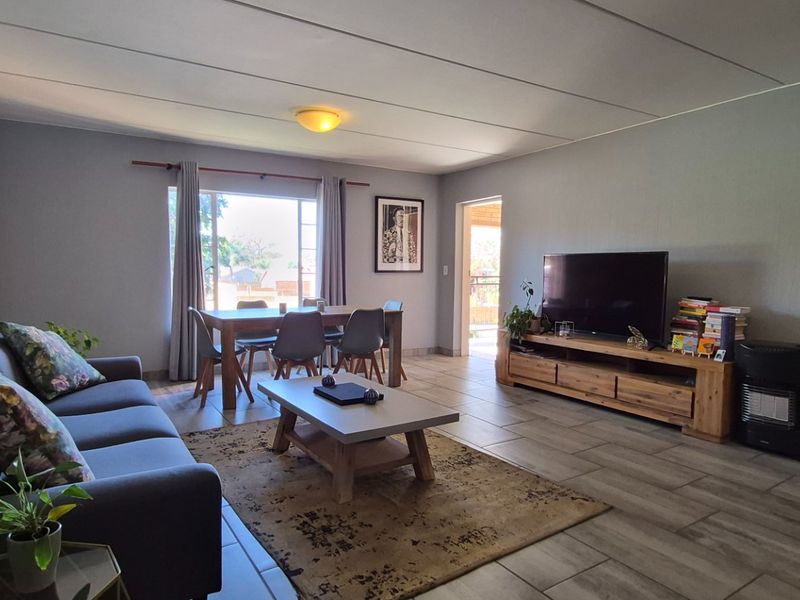 A spacious living room featuring tiled flooring and neutral wall finishes, providing a comfortable and functional area for relaxation and dining.