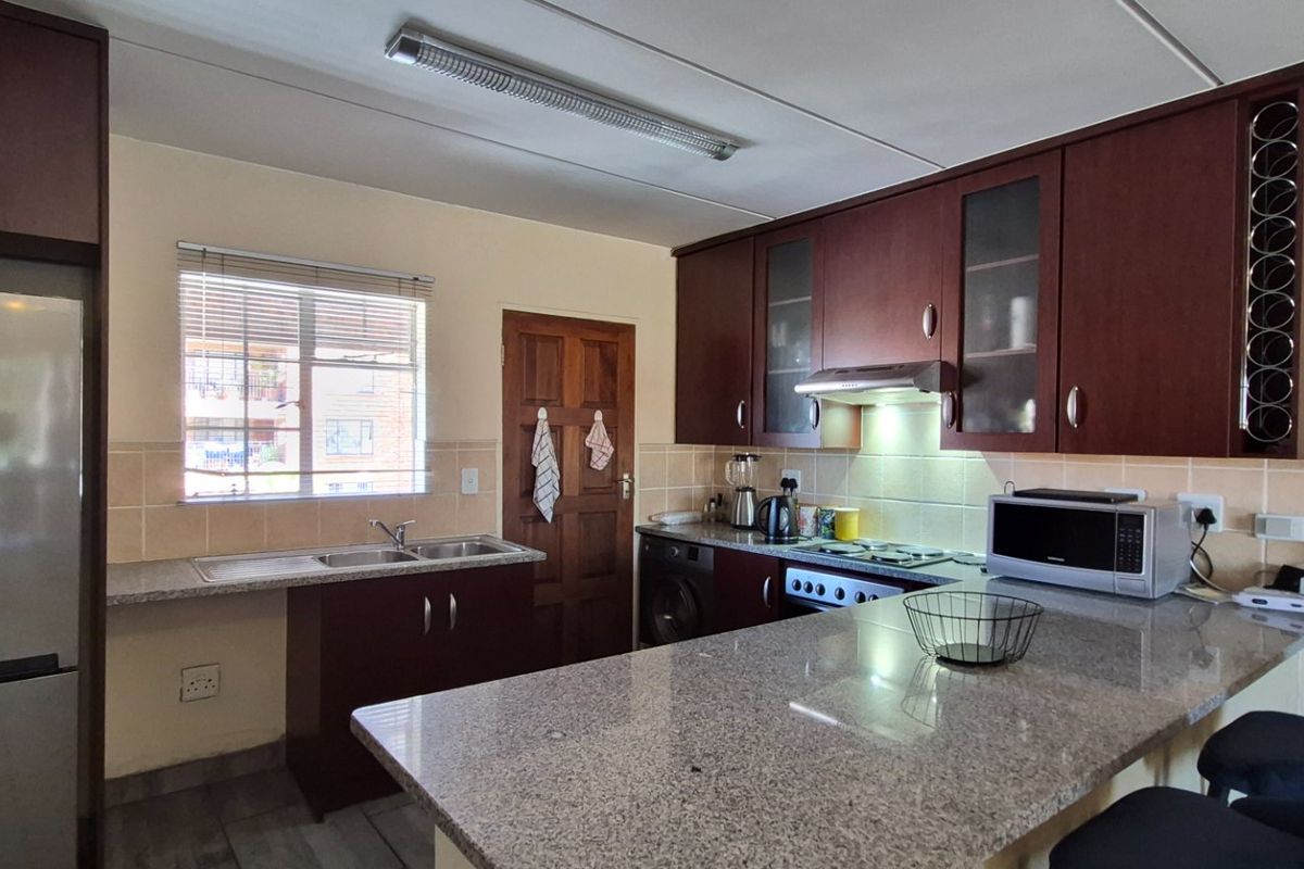 Functional kitchen featuring dark wood cabinetry, granite countertops, a breakfast nook, and a tiled backsplash with integrated appliances.