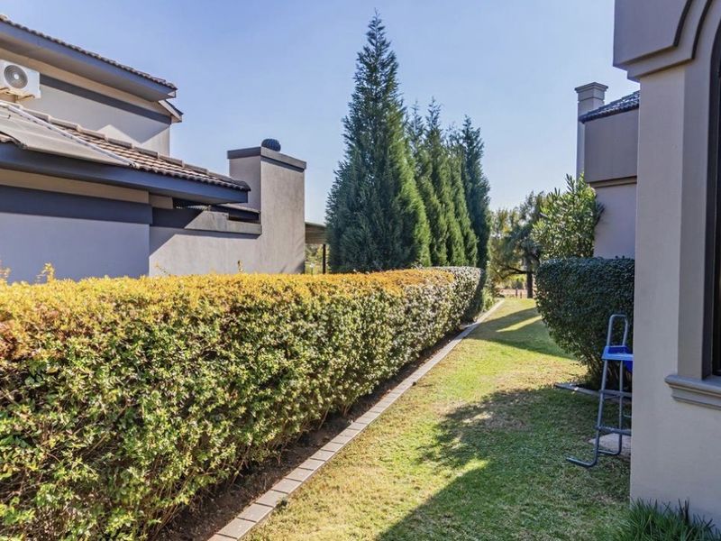 A well-maintained rear garden area featuring manicured hedging, a neat lawn, and clear views of the property's exterior architecture.