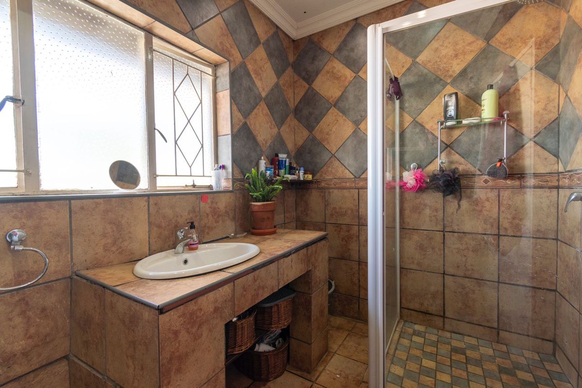 A functional bathroom featuring a tiled vanity with a drop-in basin, a separate shower enclosure, and full-height wall tiling.