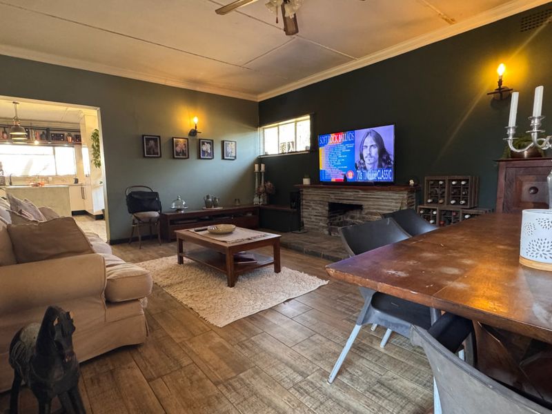 Spacious open-plan living and dining area featuring a stone fireplace, tiled flooring, and direct access to the adjoining kitchen.