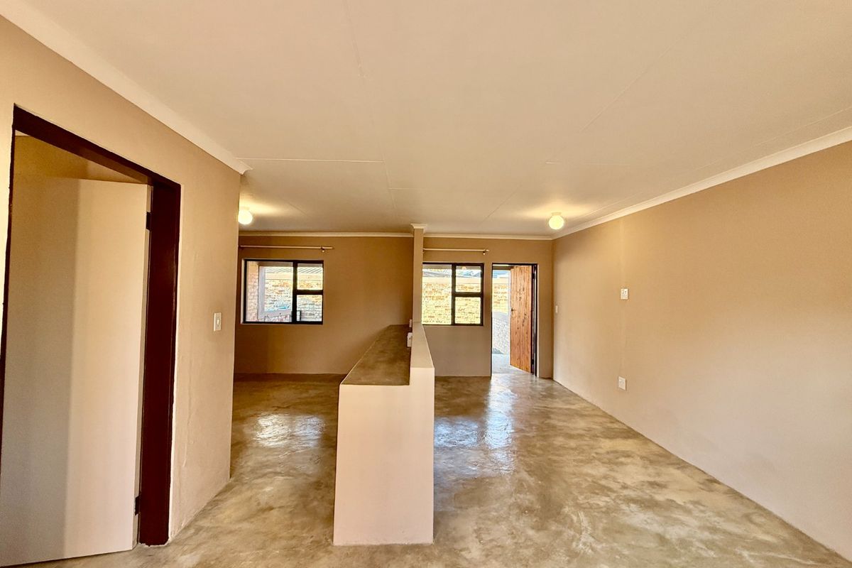 An open-plan living area featuring polished concrete floors, neutral wall tones, and a central partition wall, offering a versatile blank canvas for interior design.