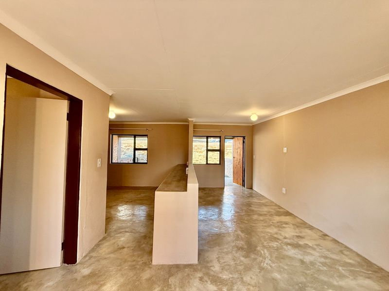 An open-plan living area featuring polished concrete floors, neutral wall tones, and a central partition wall, offering a versatile blank canvas for interior design.