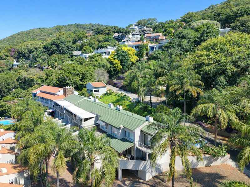 Aerial view of the apartment complex nestled in a lush, hillside residential area with mature trees and established landscaping.