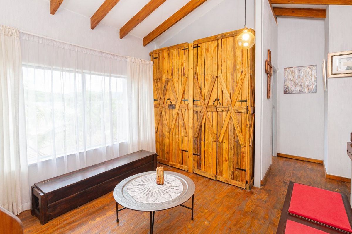 Bedroom featuring exposed timber ceiling beams, rustic built-in timber wardrobe, and warm timber flooring, offering a cozy and character-filled living space.