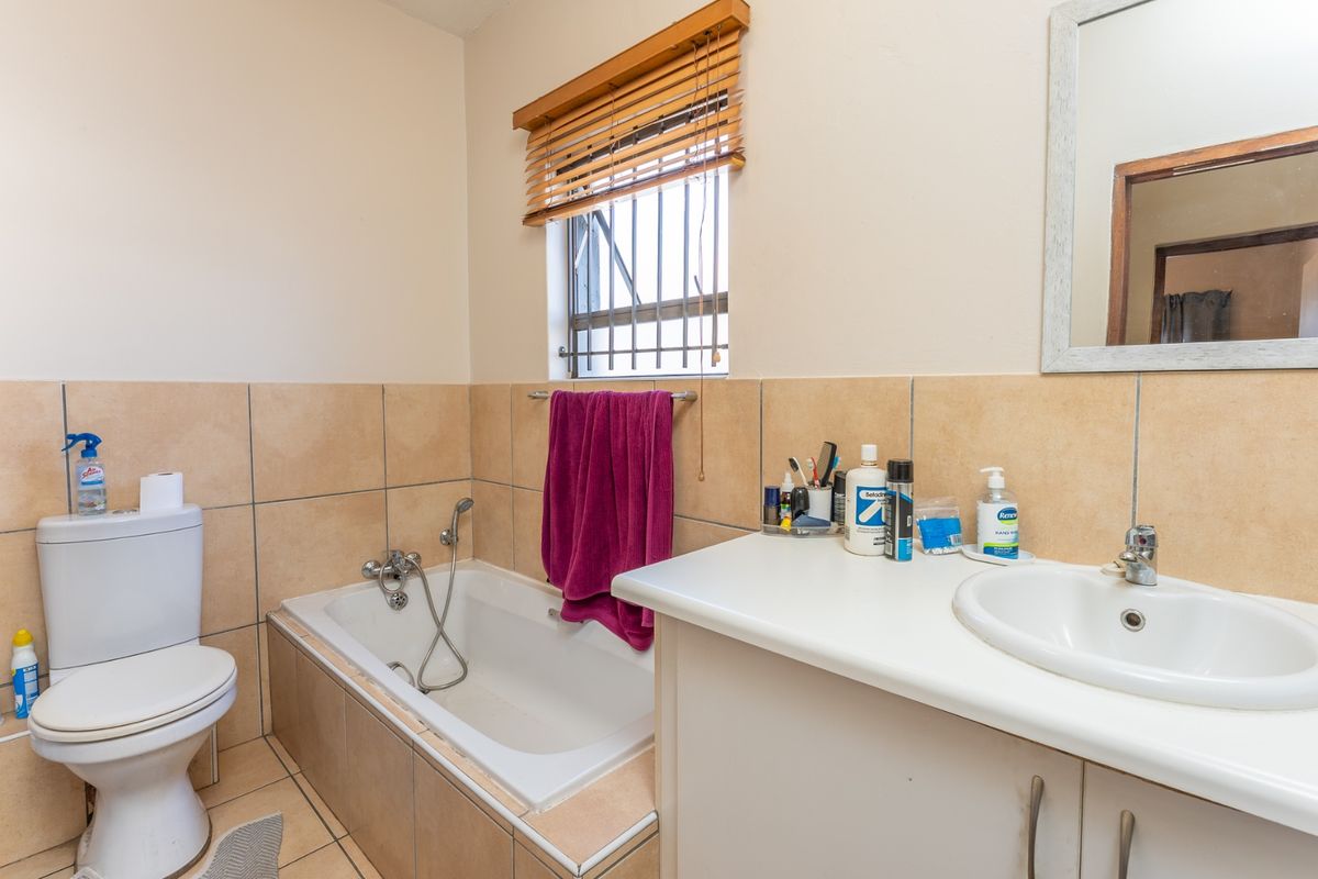 A functional bathroom featuring a built-in vanity with basin, a drop-in bathtub, and tiled finishes, offering a practical layout for daily use.