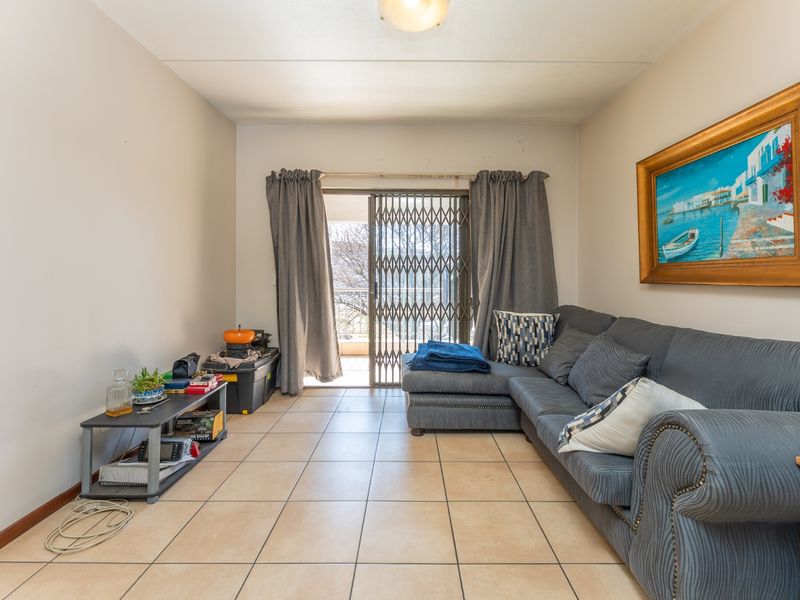 Living room featuring tiled flooring and a sliding glass door with a security gate leading to an outdoor area.