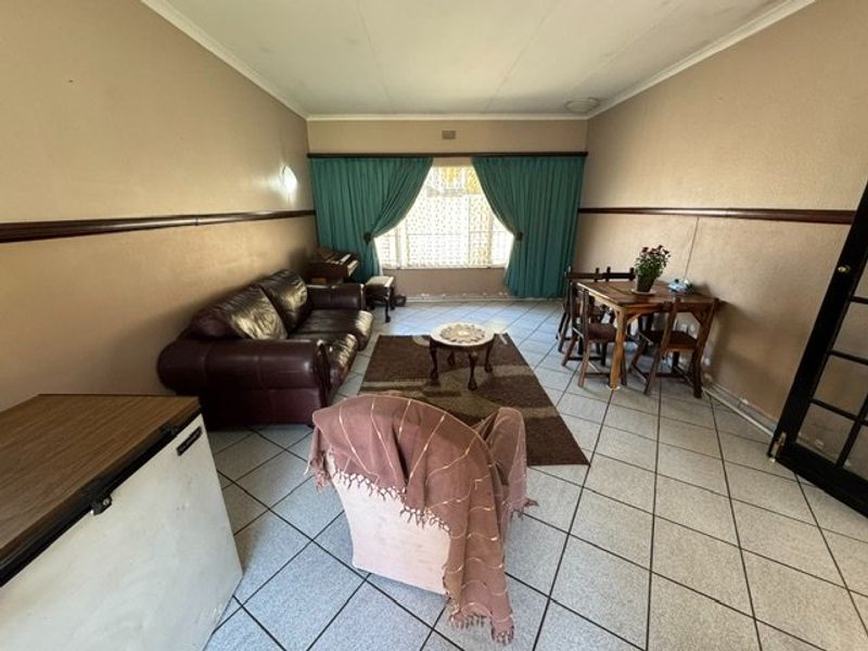 A living room featuring tiled flooring and a dado rail, offering a functional space with potential for cosmetic updates to modernize the interior.