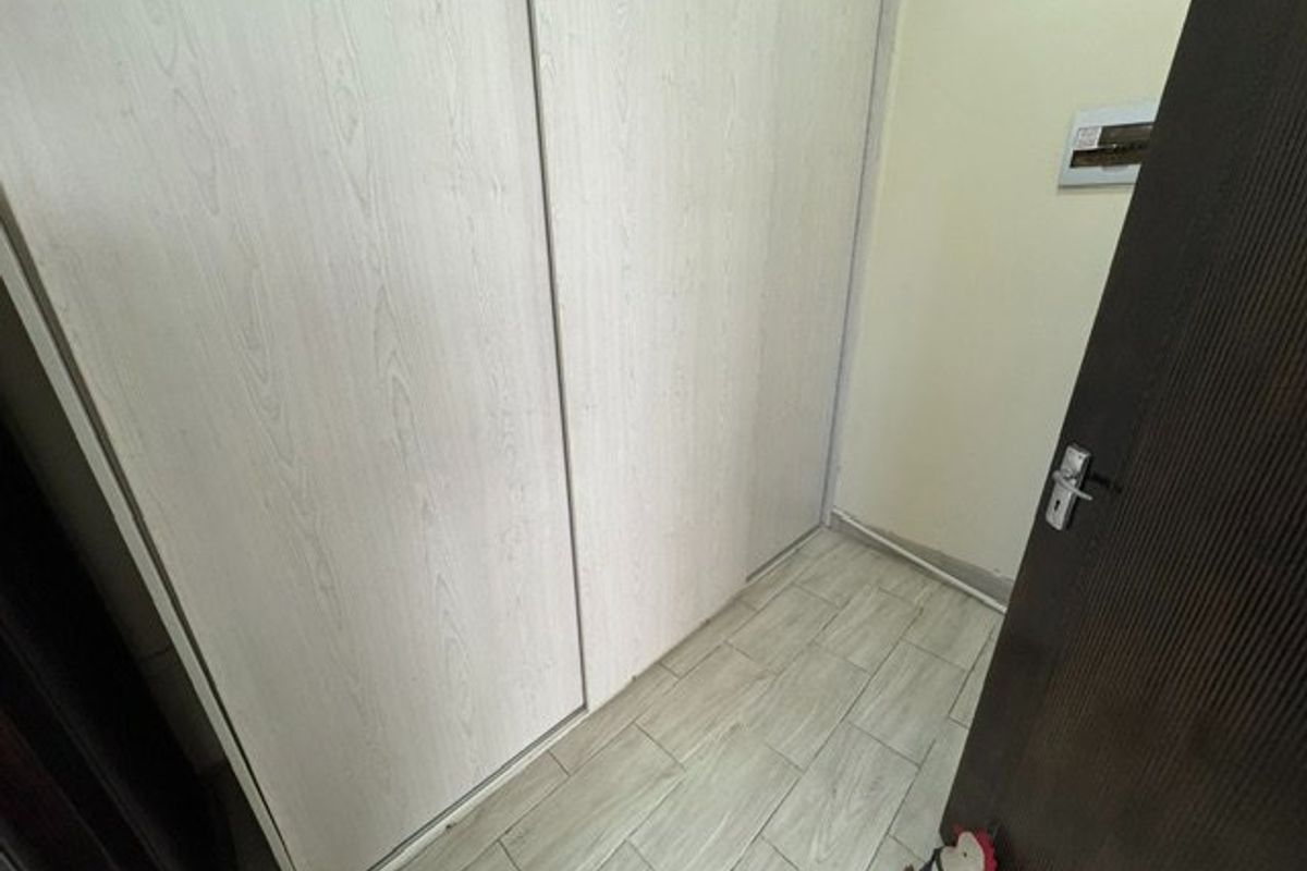 A clean bedroom space featuring light wood-look tiled flooring and a large built-in sliding door wardrobe.
