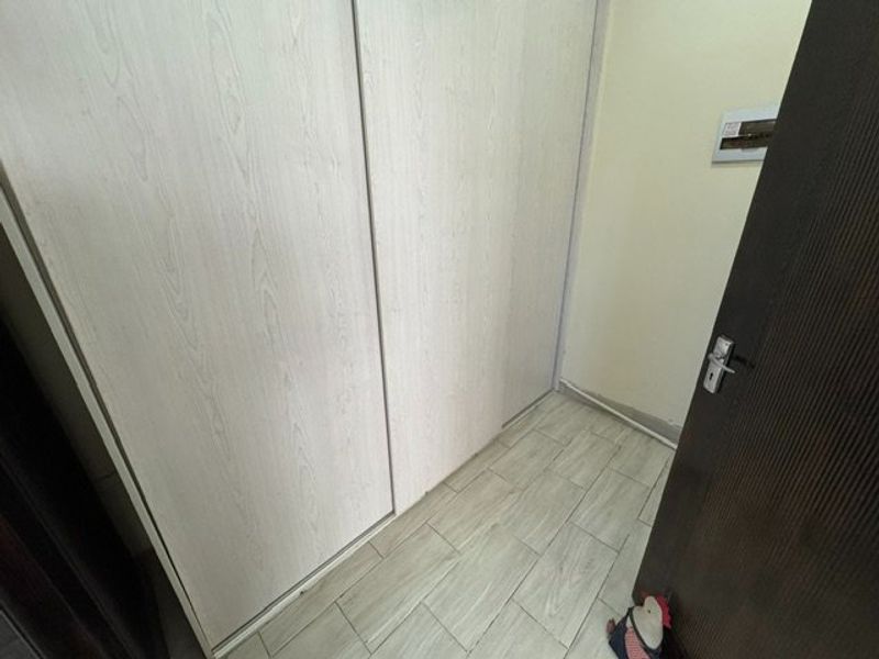 A clean bedroom space featuring light wood-look tiled flooring and a large built-in sliding door wardrobe.