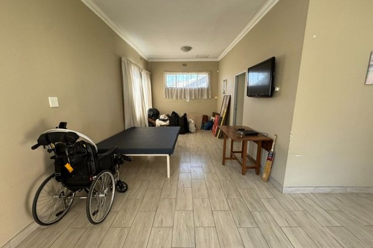A spacious living area featuring light-toned tiled flooring and coved ceilings, offering a neutral canvas for potential interior updates.