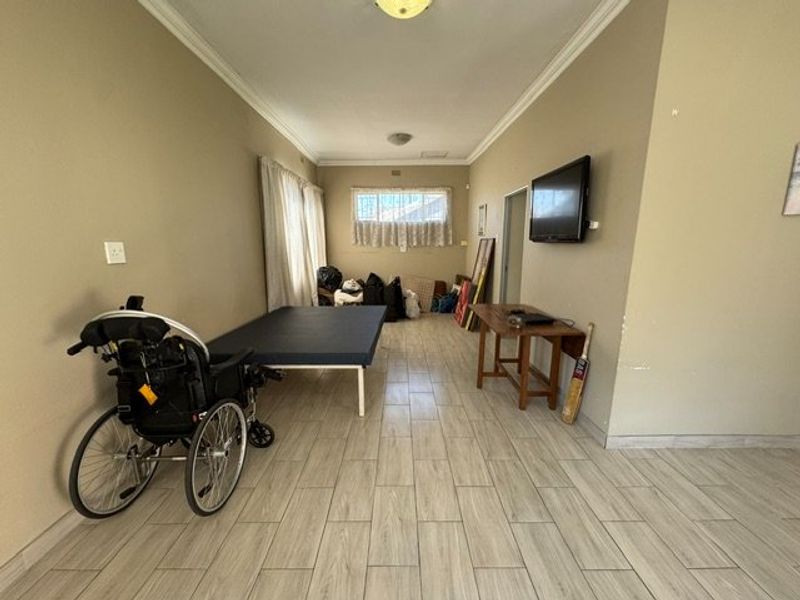 A spacious living area featuring light-toned tiled flooring and coved ceilings, offering a neutral canvas for potential interior updates.