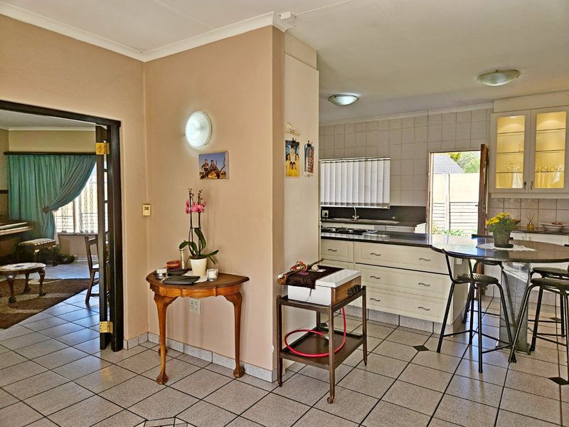 Open plan kitchen and living area featuring tiled flooring, granite countertops, and classic cabinetry, offering a functional layout with direct access to the exterior.
