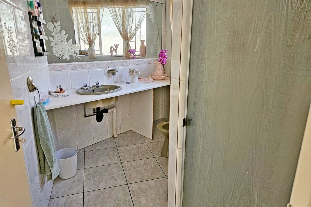 A dated bathroom featuring a vanity basin, tiled surfaces, and a shower enclosure, requiring modernization to improve functionality and aesthetic appeal.