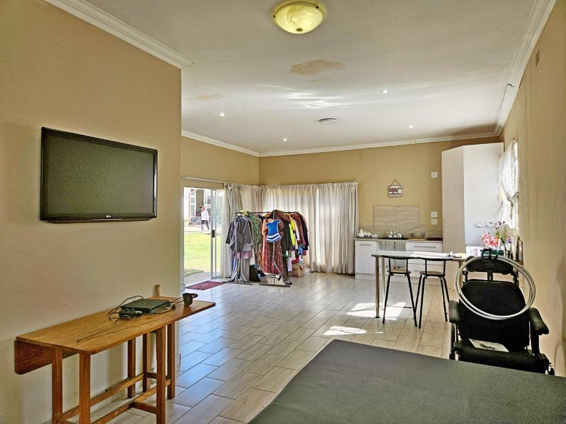 Open-plan living and kitchen area featuring tiled flooring, recessed lighting, and direct access to the garden through sliding glass doors.