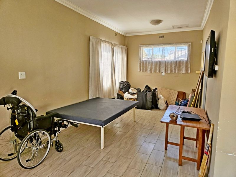 A bedroom featuring tiled flooring and security bars on the window, offering a functional space ready for personalization.
