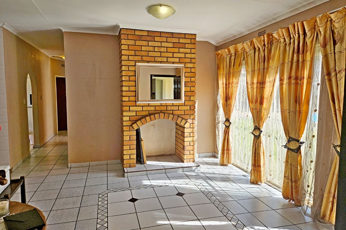 Spacious living room featuring a central brick fireplace, ceramic tiled flooring, and large sliding glass doors providing access to the exterior.