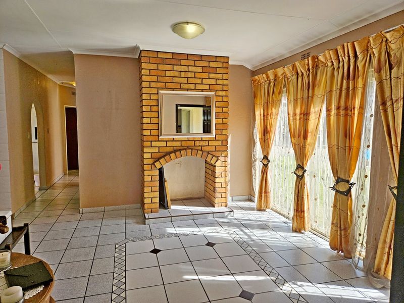 Spacious living room featuring a central brick fireplace, ceramic tiled flooring, and large sliding glass doors providing access to the exterior.