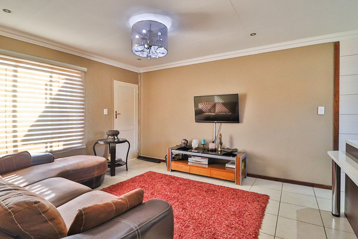 A comfortable living room featuring tiled flooring, neutral wall finishes, and modern roller blinds, providing a functional and well-lit space.
