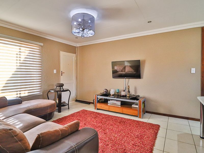 A comfortable living room featuring tiled flooring, neutral wall finishes, and modern roller blinds, providing a functional and well-lit space.