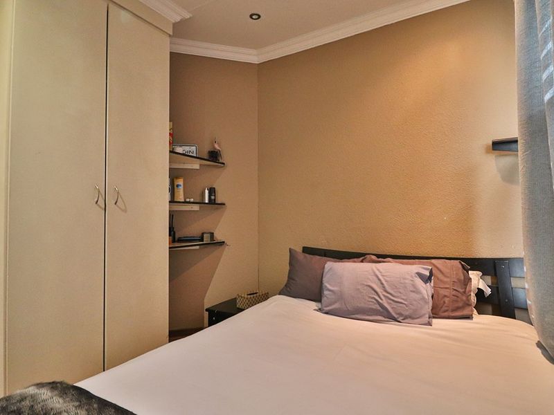 A cozy bedroom featuring a built-in wardrobe, recessed ceiling lighting, and decorative coving, providing a functional and compact sleeping space.