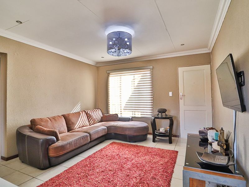A living room featuring tiled flooring, neutral wall finishes, and a ceiling with recessed lighting and cornice detailing.