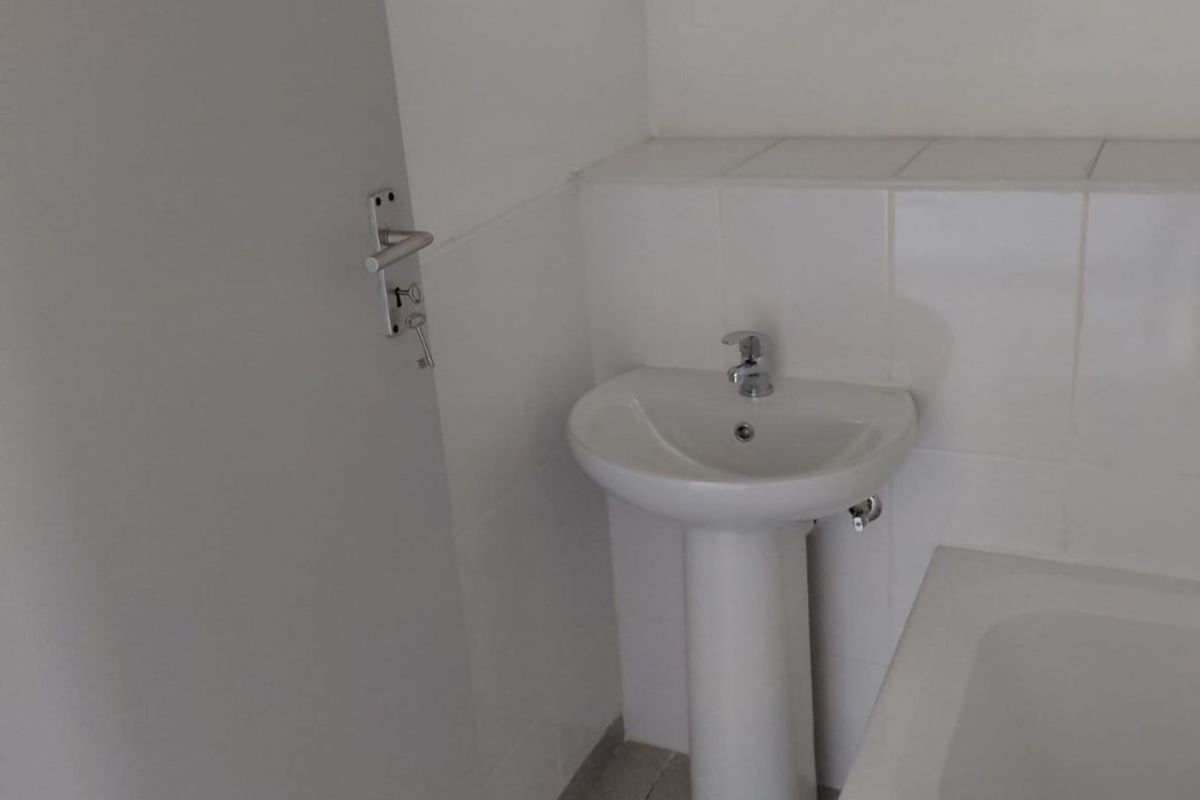 A functional bathroom featuring a pedestal basin, chrome fixtures, a built-in bathtub, and a wall-mounted medicine cabinet with neutral tiled finishes.