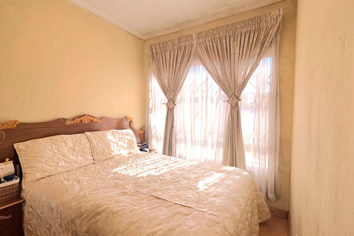 A compact bedroom featuring neutral wall finishes and natural light through window treatments.